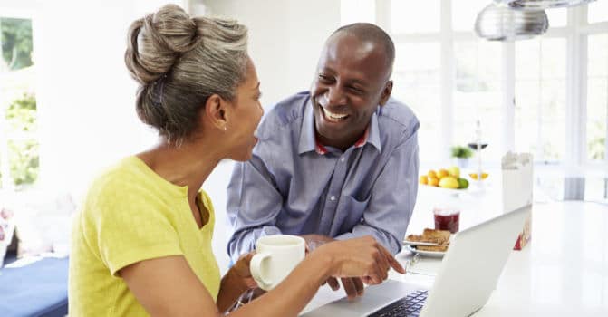 smiling middle-aged couple looking at laptop together