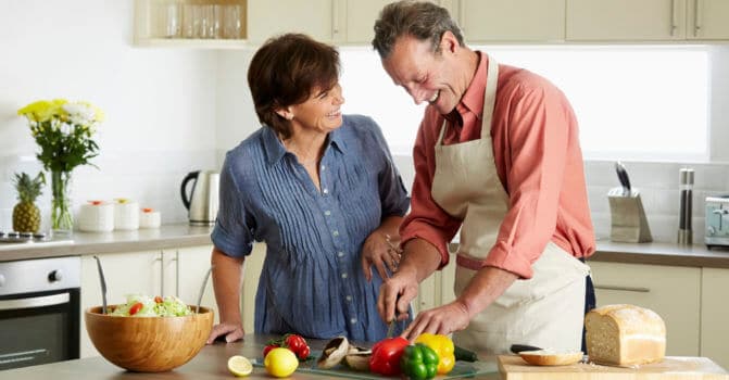 smiling middle-aged couple cooking dinner